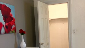 Ein Flur mit einer weißen Tür, einem weißen Schreibtisch mit einer Vase roter Rosen und einem Gemälde von roten Rosen an der Wand.