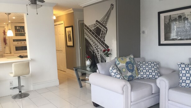 Ein modernes Wohnzimmer mit einem weißen Sofa, einem Glastisch und einem Deckenventilator.