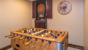 A foosball table in a room with a dartboard and a clock on the wall. - Luxury 5 Bedroom Big Sky Retreat (Big Sky)