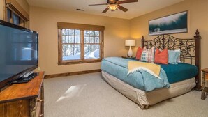A bedroom with a bed, a television, a window, and a ceiling fan. - Luxury 5 Bedroom Big Sky Retreat (Big Sky)