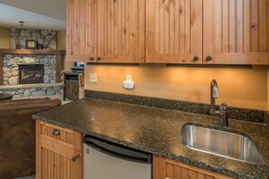 Eine Küche mit Holzausstattung, einem Steinofen, einer Granitarbeitsplatte und einem Edelstahlbecken.
