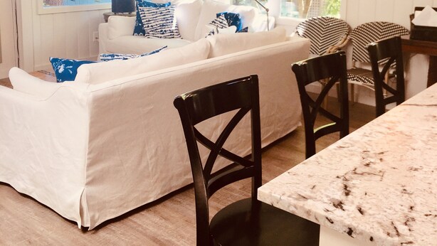 A cozy room with a white sofa, two black chairs, a marble table, and a window with a view of trees. - Eagle Harbor View Cottage (Bainbridge Island)