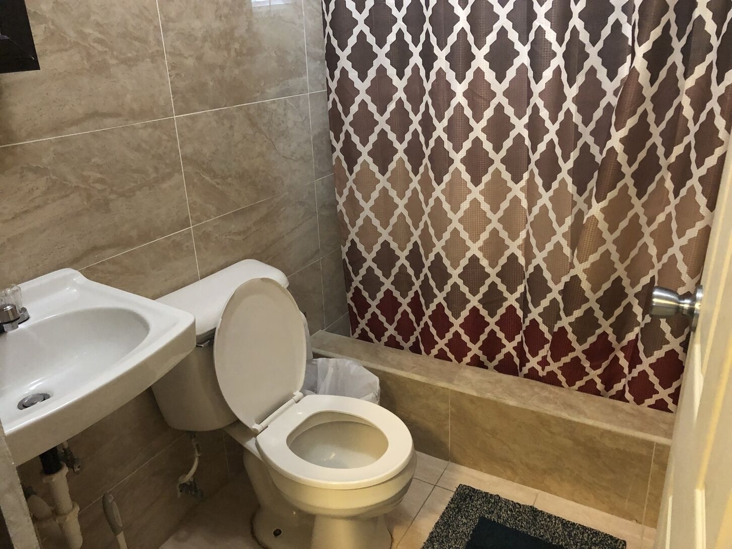 Une salle de bain équipée de toilettes, d’un lavabo et d’un rideau de douche à motifs.