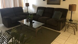A living room with two dark brown sofas, a glass coffee table, a small potted plant, and a framed picture on the wall. - PEDRO'S PLACE PRIVATE APARTMENT 2 BDRM 1 ba Free Power, Water and Internet (Sinajana)