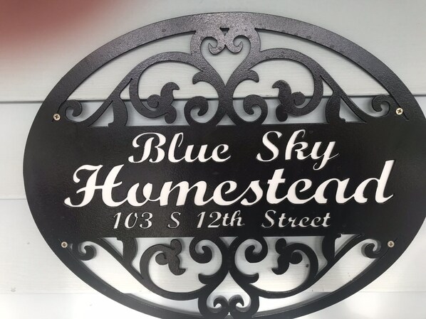 A circular metal sign with the text 'Blue Sky Homestead 103 S 12th Street'. - Blue Sky Homestead!! (Bethany)