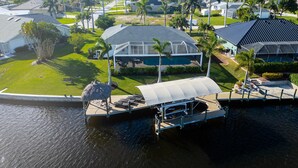 A waterfront property with a dock, a covered boat launch, and a swimming pool. - Lovely waterfront gulf access, heated pool in SW Cape Coral awaits you. (Cape Coral)