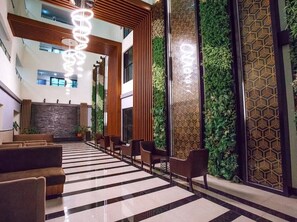 Experience the sleek, modern lobby with a central staircase, plush seating area, and striking chandelier.