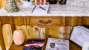 Una taula de fusta amb una superfície de marbre blanc, una làmpada de sal, un llibre, un cartell i una bossa negra amb la inscripció 'General Store'.