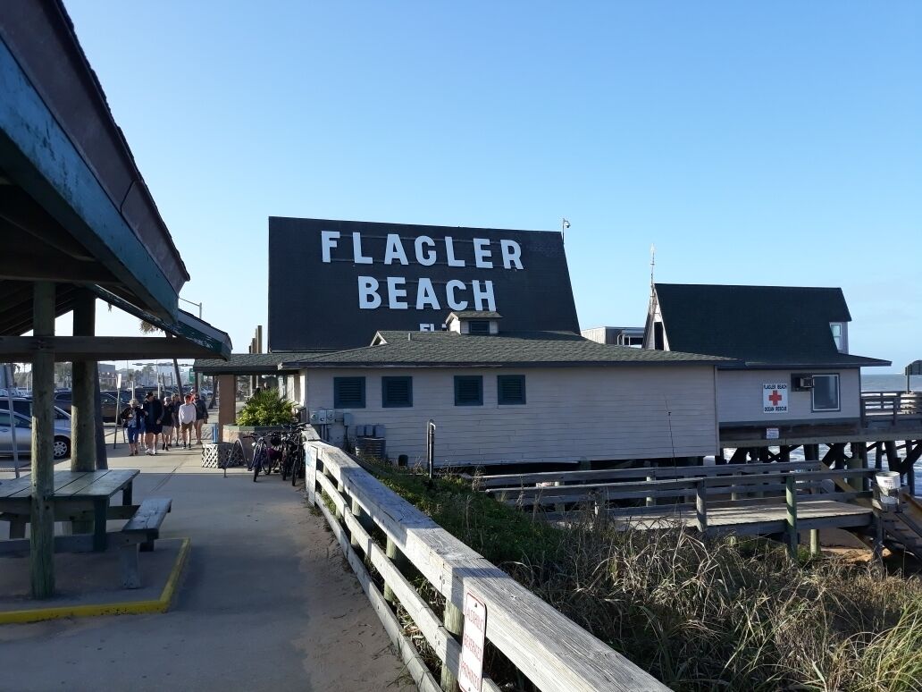 En strandpromenad med en skylt som visar texten ”FLAGLER BEACH” och en livräddarstation.