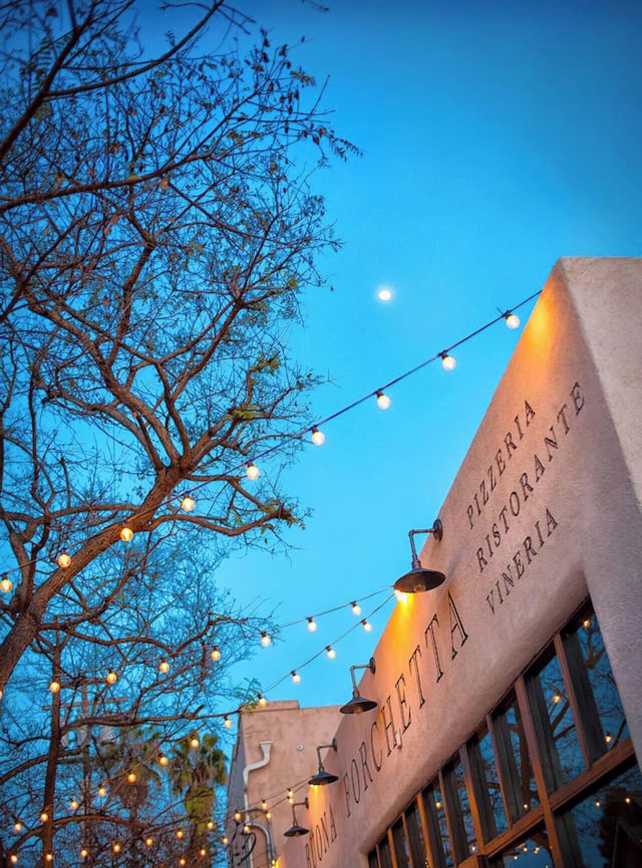 A building with a sign reading 'PIZZERIA RISTORANTE VIVERIA' and string lights.