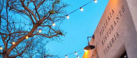 Un bâtiment sur lequel on peut lire l’inscription « PIZZERIA RISTORANTE VIVERIA » et qui est décoré de guirlandes lumineuses.