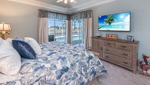 A bedroom with a bed, a ceiling fan, a TV, a dresser, and a view of a pool. -  Beautiful Southern Exposure,  with gorgeous sunsets on a waterway. (Marco Island)