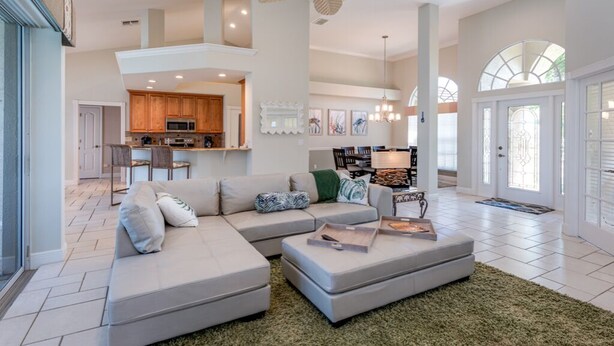 A spacious living area with a sectional sofa, a dining table, and a kitchen in the background. -  Beautiful Southern Exposure,  with gorgeous sunsets on a waterway. (Marco Island)