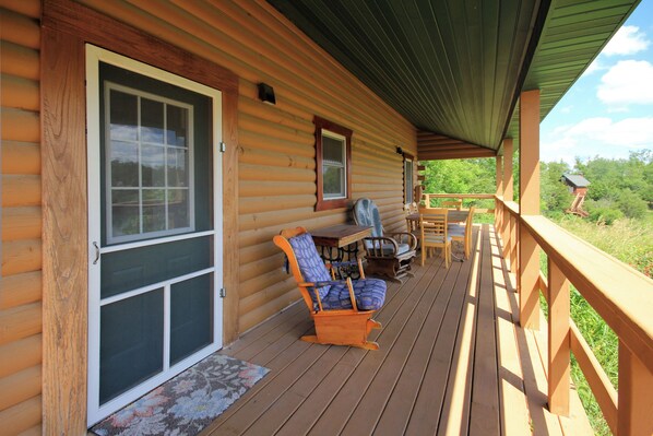 A wooden cabin with a porch, a sliding door, and outdoor seating.