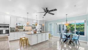 Una cucina moderna con mobili bianchi, un piano di lavoro in granito e una ventola a soffitto.