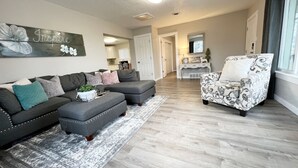 A living room with a grey sectional sofa, a patterned armchair, and a coffee table with a plant. - *Gorgeous Hideout, Close to everything, 3 bedrooms, fully remodeled!* (Salina)