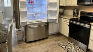 A modern kitchen with stainless steel appliances, white cabinetry, and a patterned rug. - *Gorgeous Hideout, Close to everything, 3 bedrooms, fully remodeled!* (Salina)