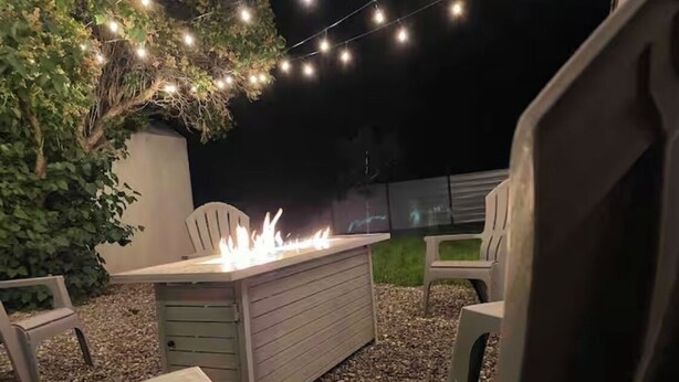 An outdoor seating area with a fire feature, surrounded by chairs and string lights. - *Gorgeous Hideout, Close to everything, 3 bedrooms, fully remodeled!* (Salina)