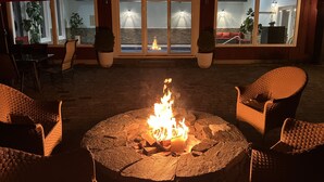 A fire pit with chairs around it, a view of the sea through large windows, and a patio area with potted plants. - SPLISH SPLASH! Explore Vermont! (Londonderry)