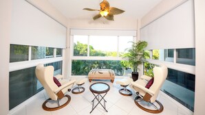 A spacious room with a ceiling fan, large windows, a sofa, two armchairs, and a small table. - 207 Mariners Club - Well appointed 3 bedroom, 3 Bath Townhome (Key Largo)