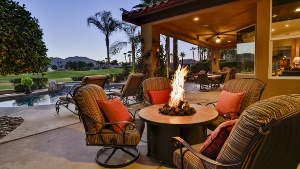 A patio with wicker furniture, a fire pit, and a pool view.