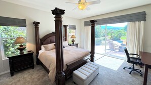 A bedroom with a four-poster bed, a desk, a chair, and a view of the outdoors.