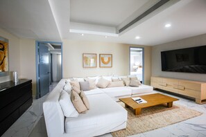 A modern living room with a sectional sofa, a coffee table, a TV, and a fireplace. - Gorgeous condo at Marina area , great views , luxury layout, jacuzzi,beach front (Puerto Vallarta)
