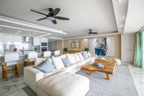 Un salon moderne avec un canapé d’angle, une table basse en bois et un ventilateur de plafond.