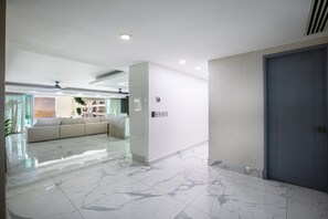 Un hall d’hôtel moderne avec un sol en marbre, un comptoir d’accueil, un canapé et une porte.