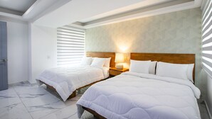 A hotel room with two beds, a wooden headboard, a nightstand with a lamp, and a door. - Gorgeous condo at Marina area , great views , luxury layout, jacuzzi,beach front (Puerto Vallarta)