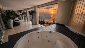 A balcony with a hot tub, potted plants, and a view of the sunset over the sea. - Gorgeous condo at Marina area , great views , luxury layout, jacuzzi,beach front (Puerto Vallarta)