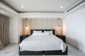 Une chambre d’hôtel moderne avec un grand lit, deux tables de chevet et un papier peint à motifs.