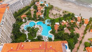Un complexe hôtelier doté de plusieurs piscines, de palmiers et d’un accès direct à la plage.