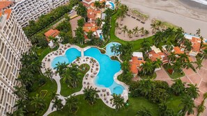 Un complexe hôtelier doté de plusieurs piscines, de palmiers et d’une plage.