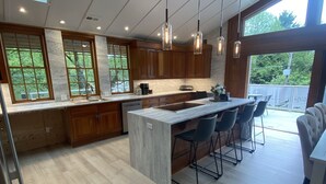 Cocina moderna con una isla grande, armarios de madera e iluminación colgante.