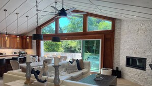 Una sala de estar moderna con un ventanal grande, una chimenea y un comedor con mesa y sillas.