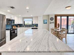 A modern kitchen with a large marble island, stainless steel appliances, and a view to the outside. - Upscale Perfection!  Beachfront Condo, End Unit  w/740 SqFt   Balcony!   Pool (panama city beach)
