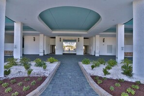 A covered entrance with a central pathway, white columns, and small plants. - Upscale Perfection!  Beachfront Condo, End Unit  w/740 SqFt   Balcony!   Pool (panama city beach)