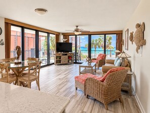 Un grand salon avec balcon, une télévision et une table à manger avec des chaises.