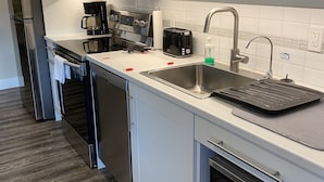A modern kitchen with white cabinets, stainless steel appliances, a coffee maker, toaster, and a microwave.