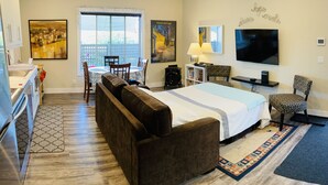 A hotel room with a bed, a desk, a chair, a TV, and a window with a city view.