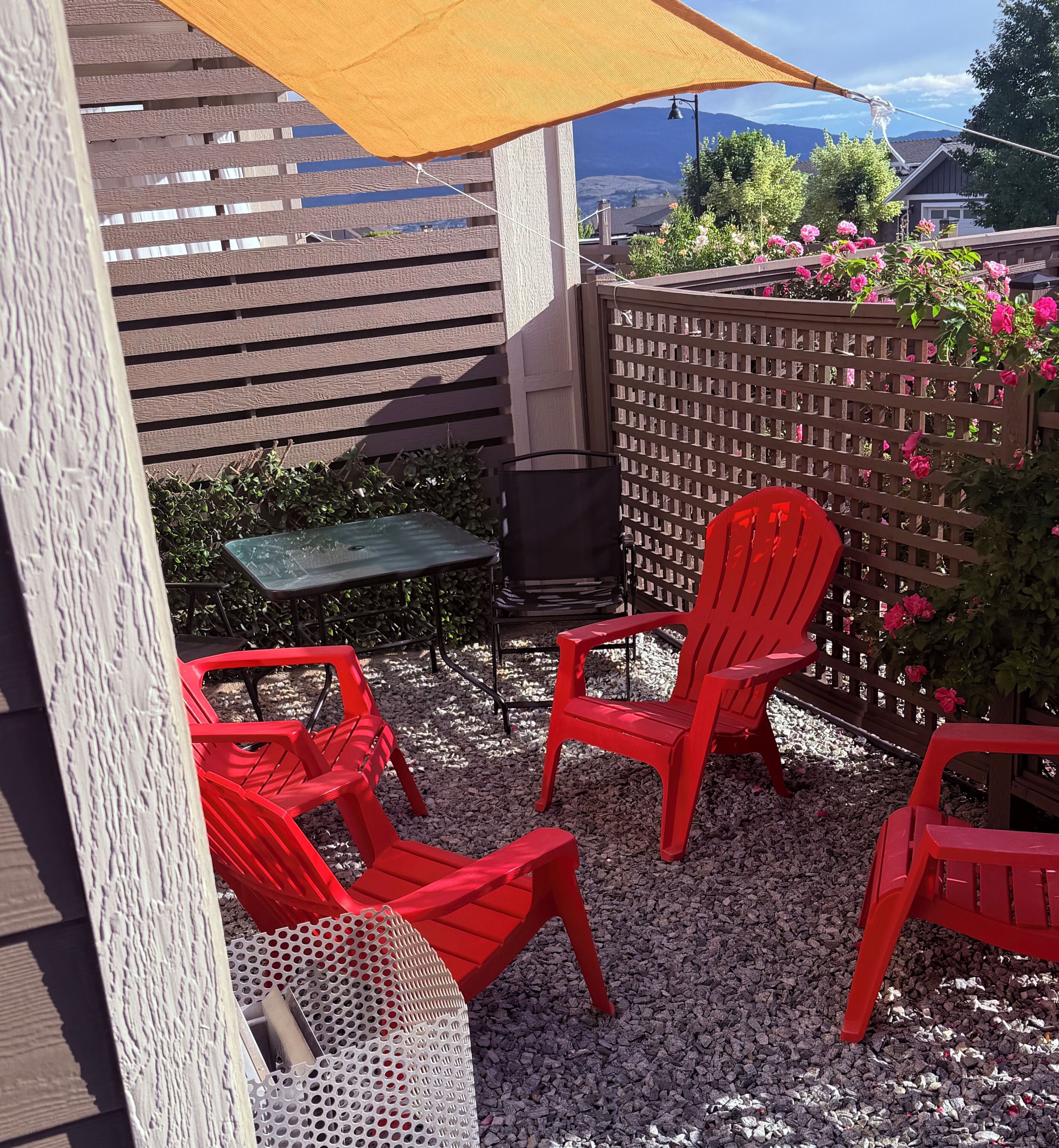 Een terras met rode stoelen, een tafeltje en een houten omheining.