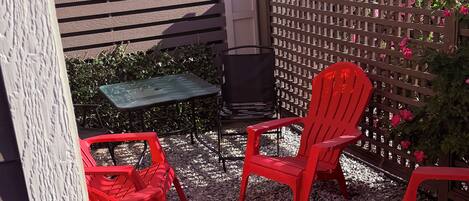 Un patio con sillas rojas, una mesita y una valla de madera.