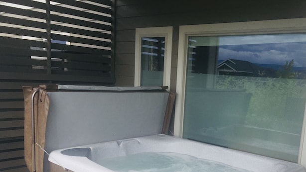 A hot tub with a wooden exterior, a control panel, and a glass window.