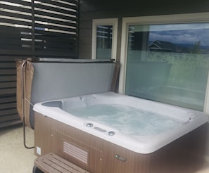 A hot tub with a wooden exterior, a control panel, and a glass window.
