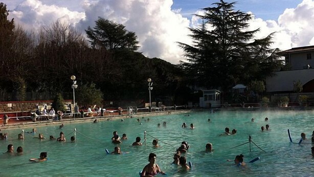 A swimming pool with people enjoying the water, surrounded by trees and buildings. - Camping Amalasunta (Montefiascone)