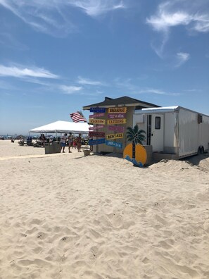 Un camion-restaurant installé au bord de la plage, avec un menu affichant des plats comme des options pour le petit-déjeuner, le déjeuner et des glaces.