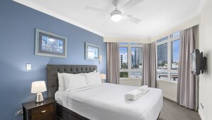 Une chambre d’hôtel avec un grand lit, un ventilateur de plafond, une télévision et une fenêtre avec des rideaux.