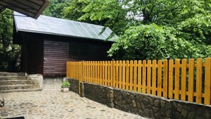 A stone-paved courtyard with a wooden fence and a building with a metal roof. - Apartment Carol (Sinaia)