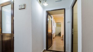 A hallway with wooden flooring, a door on the left, and a light fixture above. - Apartment Carol (Sinaia)